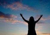 14157683-woman-staying-with-raised-hands-at-the-sunset-time
